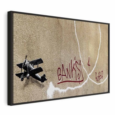 ⁨Obraz - Samolot Banksy (1-częściowy) - graffiti czerwone napisy na tle muralu (rozmiar 90x60, wykończenie W ramie drewnianej czarnej)⁩ w sklepie Wasserman.eu