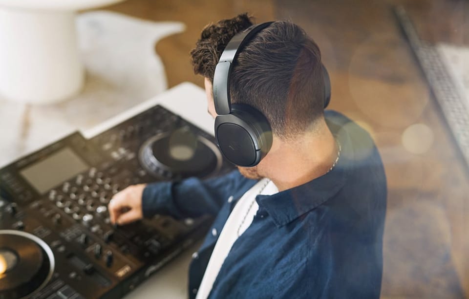 mężczyzna nad mikserem dźwięku z czarnymi słuchawkami na głowie