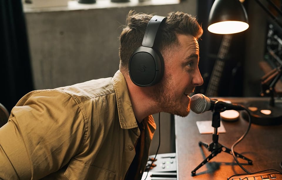mężczyzna mówiący coś do mikrofonu w studiu, na głowie ma czarne słuchawki