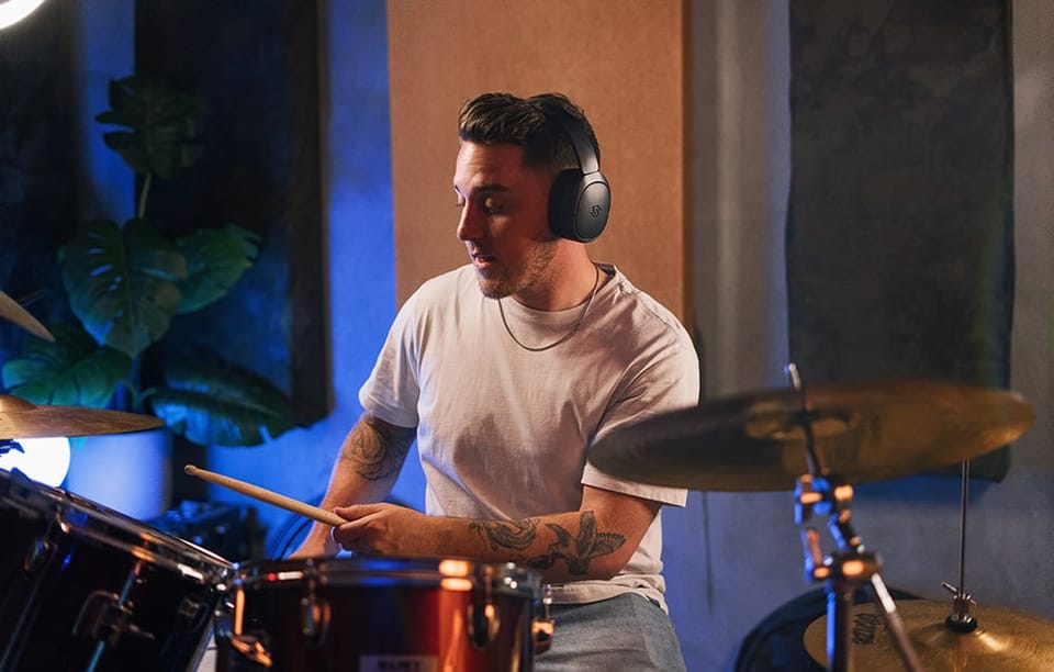 mężczyzna z czarnymi słuchawkami na głowie grający na perkusji