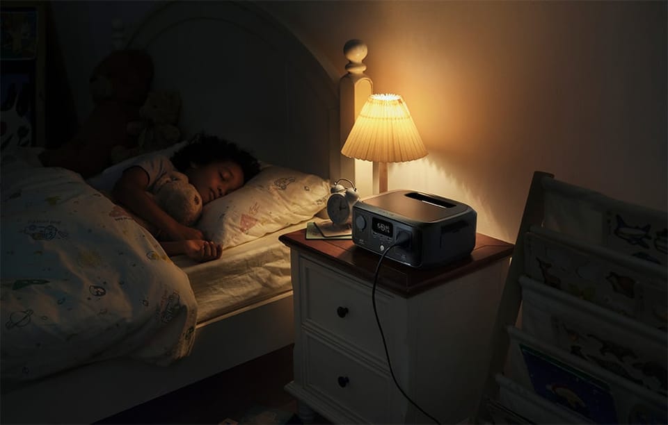 Małe dziecko śpi w łóżku przy zapalonej lampce nocnej, obok której stoi stacja EcoFlow RIVER 3