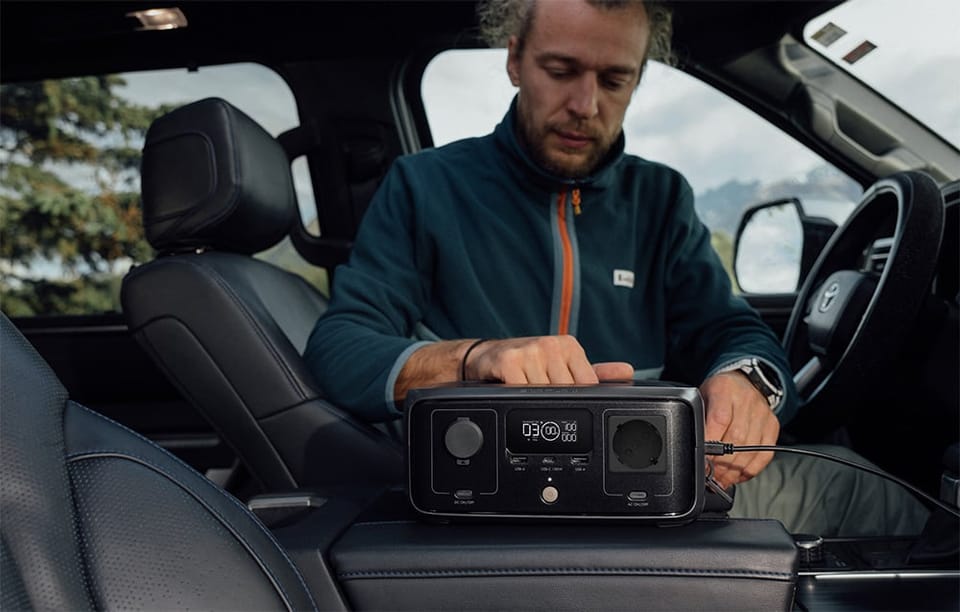 Mężczyzna siedzi w samochodzie i obsługuje stację EcoFlow RIVER 3 ustawioną na konsoli środkowej