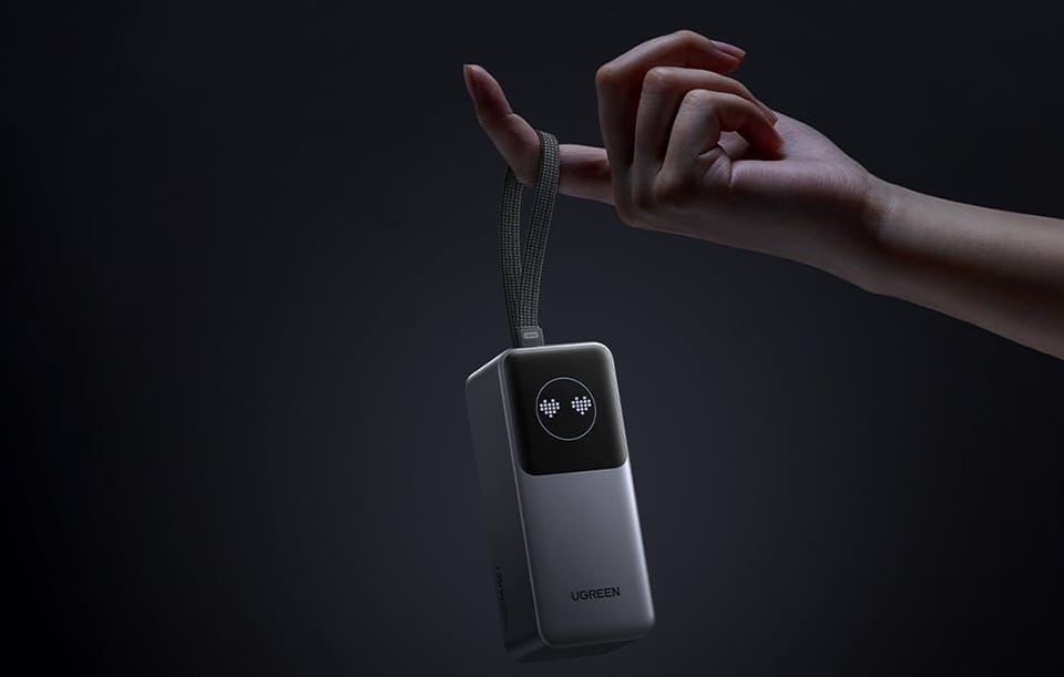 Powerbank Ugreen zawieszony na palcu za pomocą paska transportowego