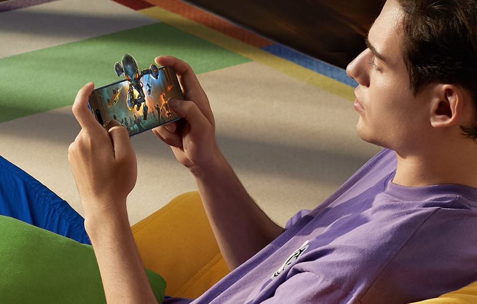 Mężczyzna w fioletowej koszulce leży na kanapie i gra na smartfonie w grę akcji z dynamiczną grafiką 3D