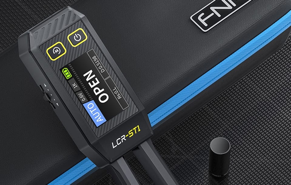 Elektroniczna pęseta leży na czarnej powierzchni obok etui, wyświetlając na ekranie komunikat „OPEN”.