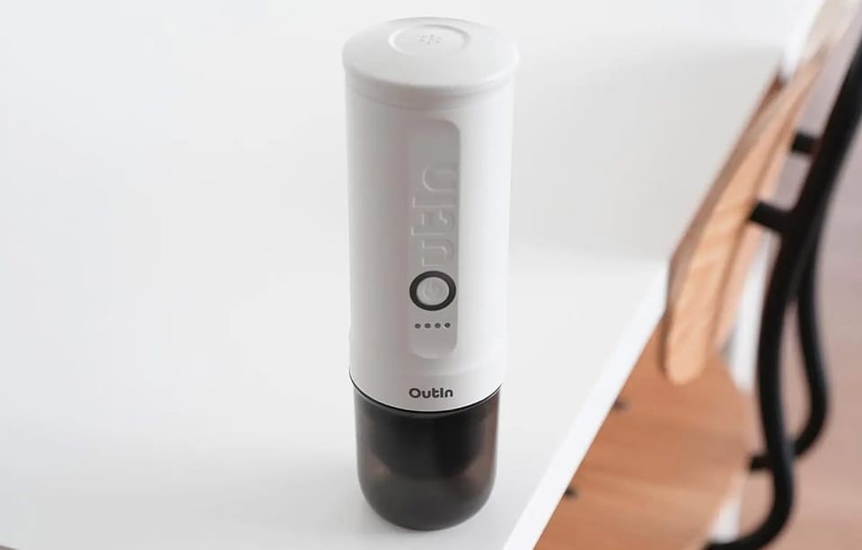 Bezprzewodowy ekspres do kawy Outin leży na białym stole.