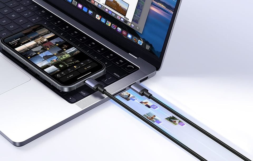 MacBook z podłączonym iPhone'em i kablem USB-C na białym tle, widoczny transfer zdjęć