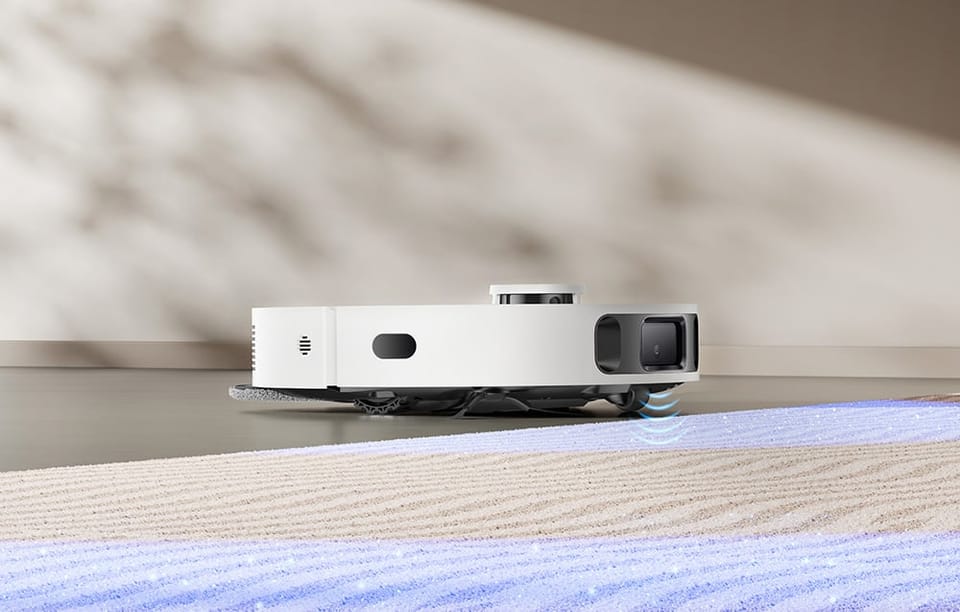 Robot sprzątający przejeżdża z twardej podłogi na dywan, skanując powierzchnię przed sobą.