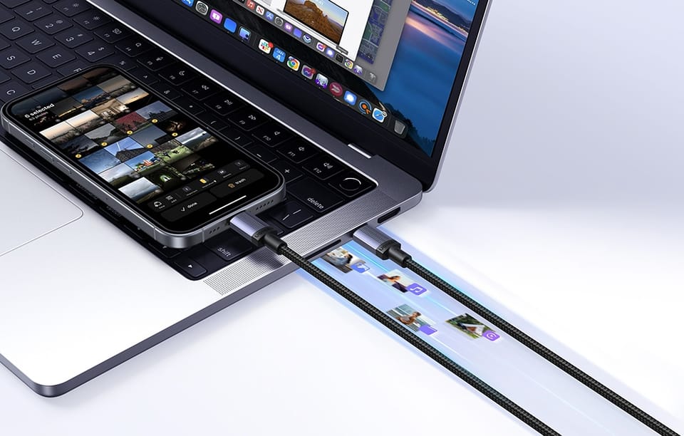 MacBook z podłączonym iPhone'em i kablem USB-C na białym tle, widoczny transfer zdjęć