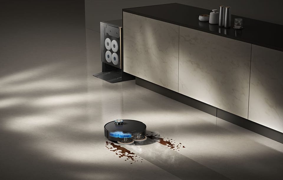 Robot sprzątający Dreame Matrix10 Ultra mopujący brudną podłogę w kuchni, w tle widać stację dokującą.
