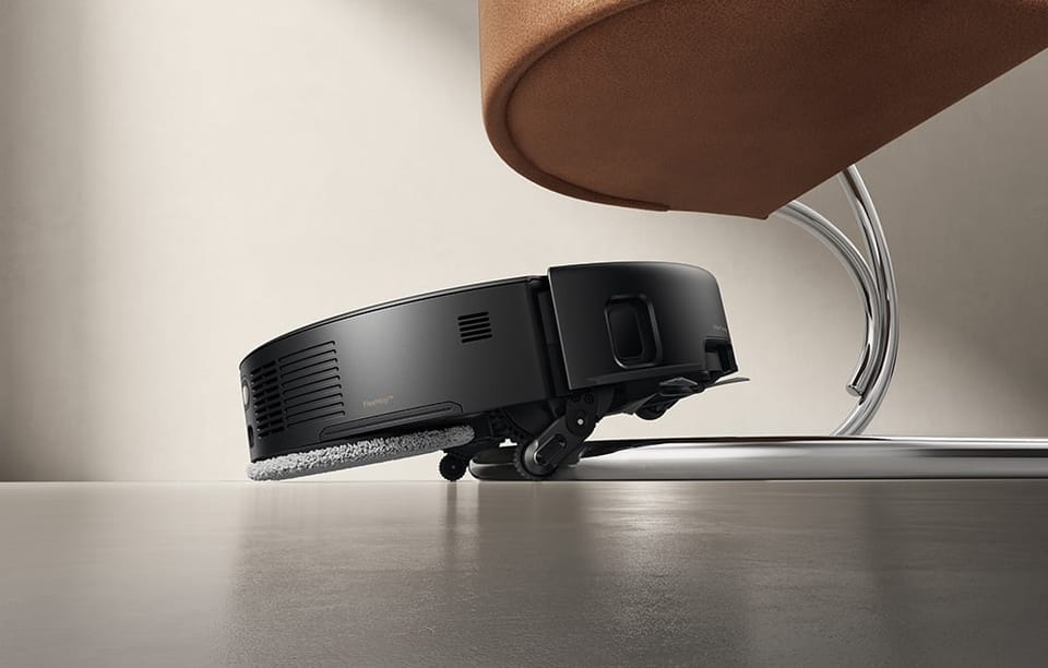 Czarny robot sprzątający odkurza podłogę.