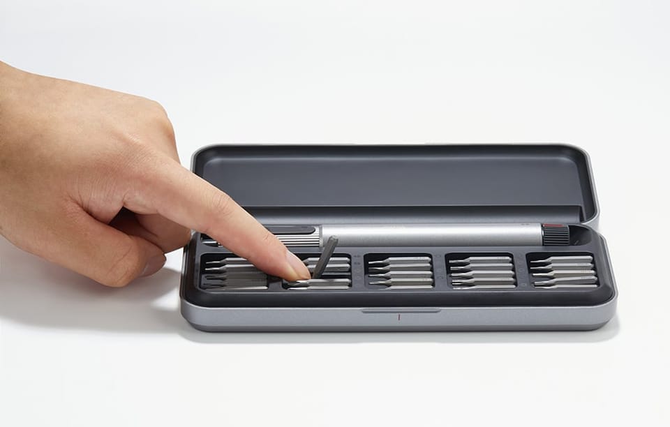 Dłoń wyjmująca bit z etui na szarym tle