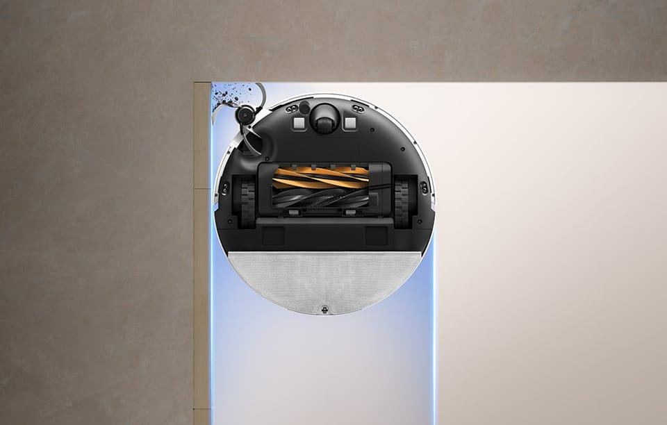 Widok od spodu robota Dreame pokazujący szczotkę główną w kolorze czarno-żółtym i boczną szczotkę zgarniającą zabrudzenia.