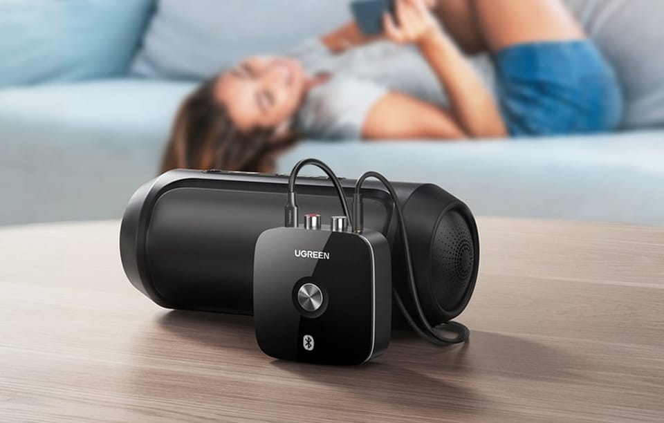 Adapter Bluetooth podłączony do czarnego głośnika na drewnianym stole