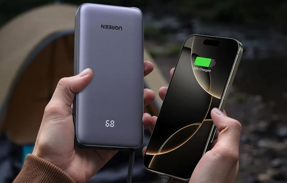 Trzymane w dłoniach smartfon i szary powerbank Ugreen z wyświetlaczem.