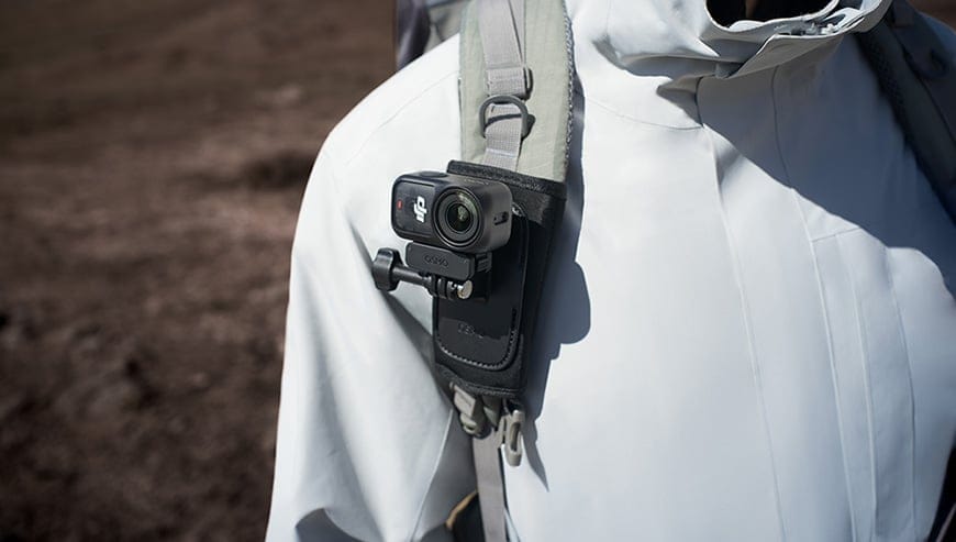 Kamera DJI Osmo Nano przymocowana do ramiączka plecaka osoby w kurtce outdoorowej