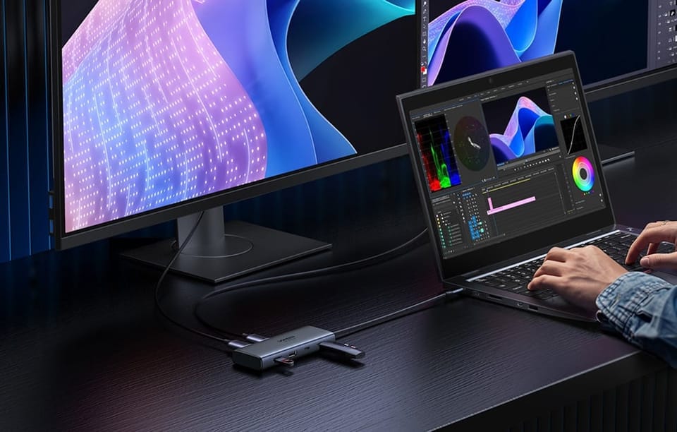 Adapter Ugreen CM498 podłączony do monitora i laptopa, na którym pracuje mężczyzna.