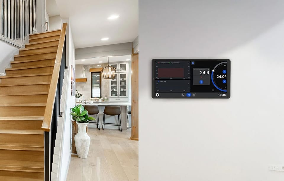 Srebrny panel Shelly X2i zamontowany na ścianie obok schodów, wyświetlający interfejs termostatu z wykresami temperatury.