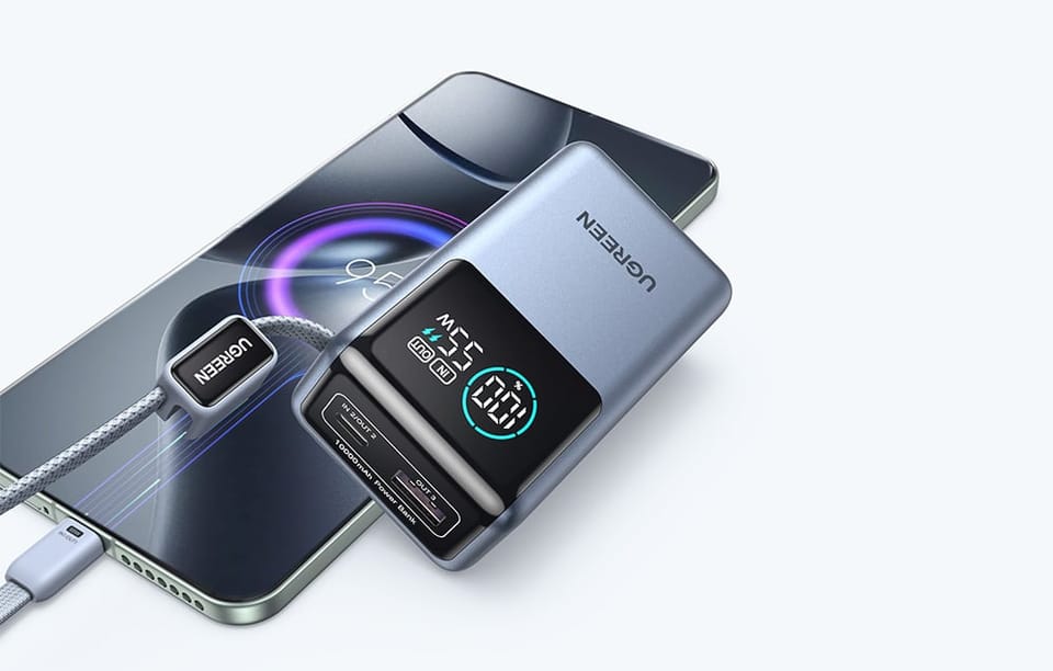 Powerbank UGREEN z ekranem pokazującym poziom baterii i moc ładowania podłączony do telefonu kablem.