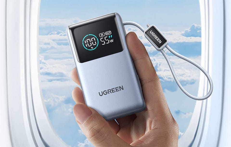 Dłoń trzyma powerbank UGREEN z wyświetlaczem poziomu baterii przy oknie samolotu.