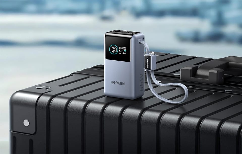 Powerbank UGREEN z wyświetlaczem poziomu baterii ustawiony na walizce podróżnej.