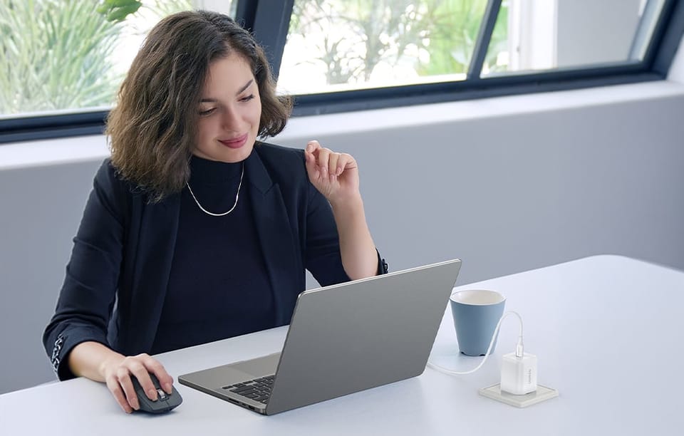 Kobieta przy laptopie podłączonym kablem do ładowarki w gniazdku 