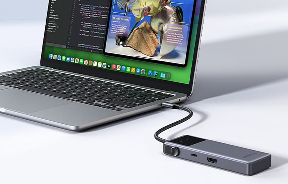 Laptop podłączony do huba USB UGREEN z widocznymi portami HDMI i USB na obudowie urządzenia.