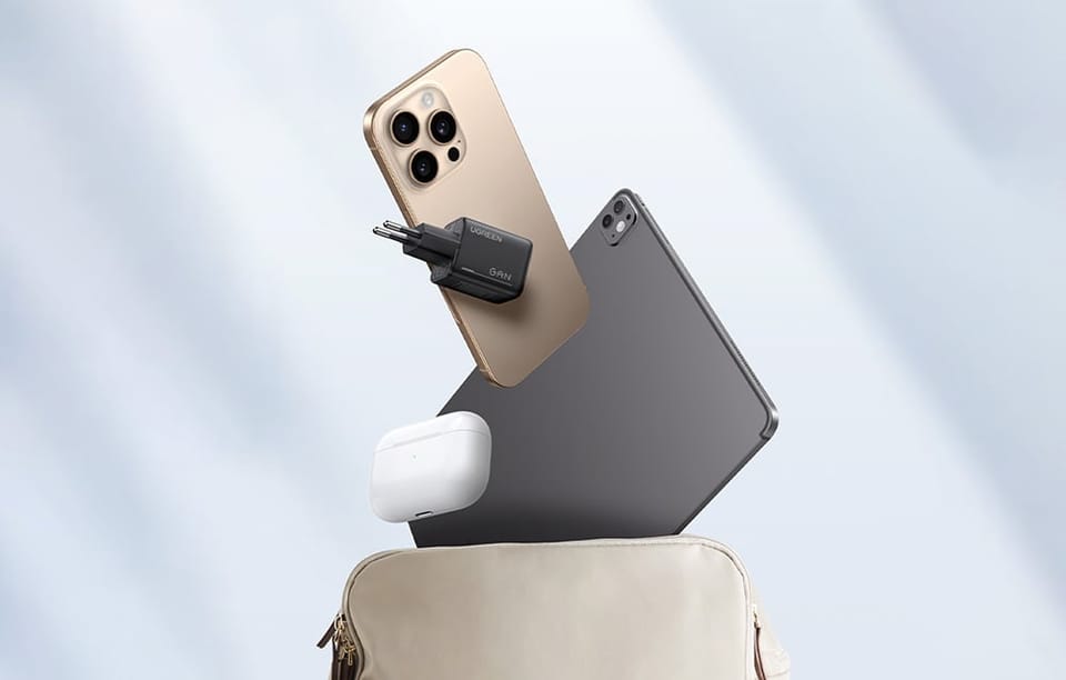 Ładowarka UGREEN GaN obok smartfona, tabletu i etui na słuchawki unoszących się nad otwartą torbą