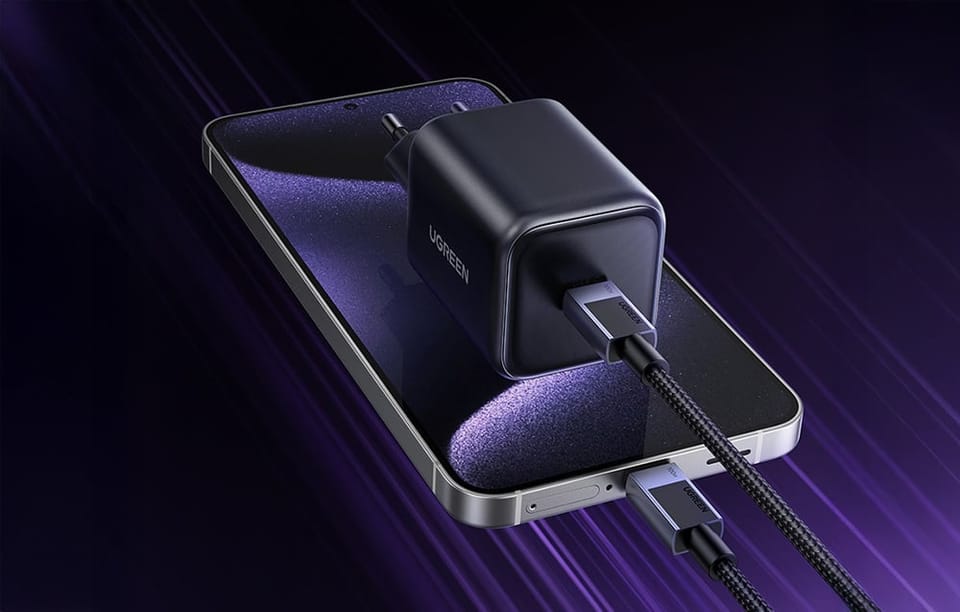 Czarna ładowarka UGREEN z podłączonym kablem USB-C leżąca na smartfonie z drugim kablem podłączonym do telefonu.