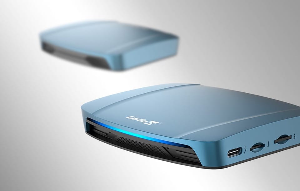 Dwa adaptery bezprzewodowe Carlinkit TBOX ULTRA, na jasnym tle, jeden rozmyty.