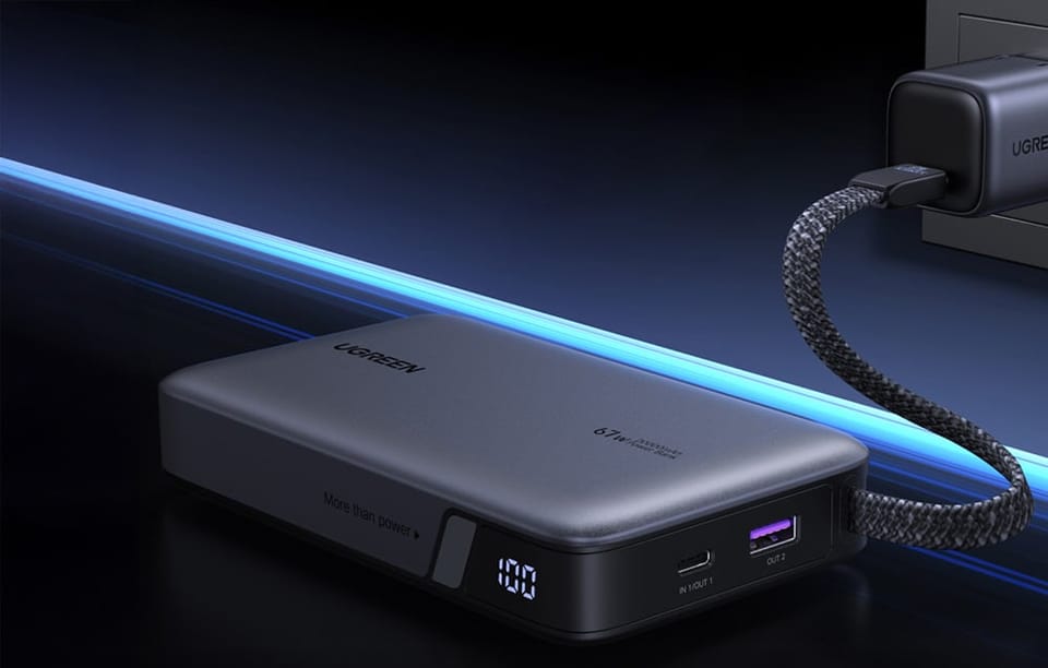 Powerbank Ugreen podłączony do ładowarki ściennej. Widoczny cyfrowy wyświetlacz wskazujący 100% naładowania oraz porty USB-C i USB-A.