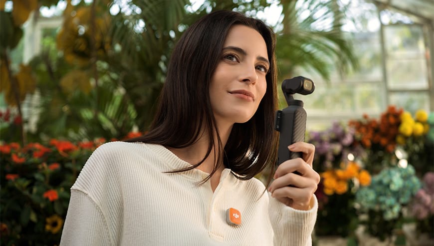 Kobieta z pomarańczowym mikrofonem DJI Mic Mini 2 trzyma kamerę sportową w szklarni