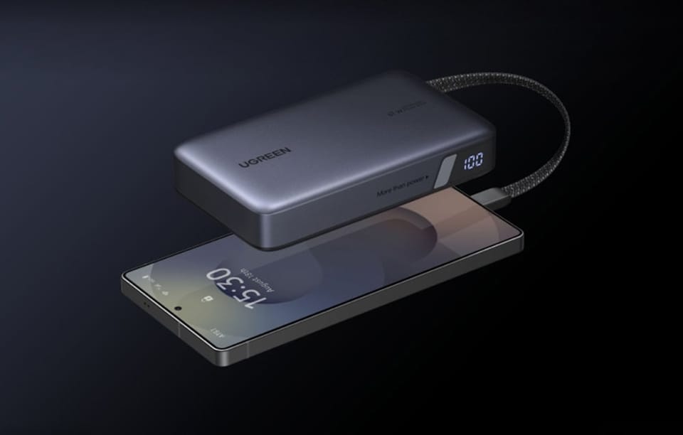 Smartfon podłączony do szarego powerbanka Ugreen na ciemnym tle