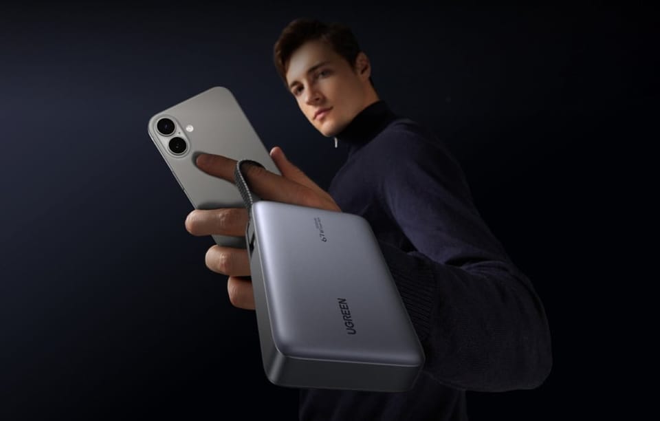 Mężczyzna trzyma w dłoni smartfon i powerbank z kablem