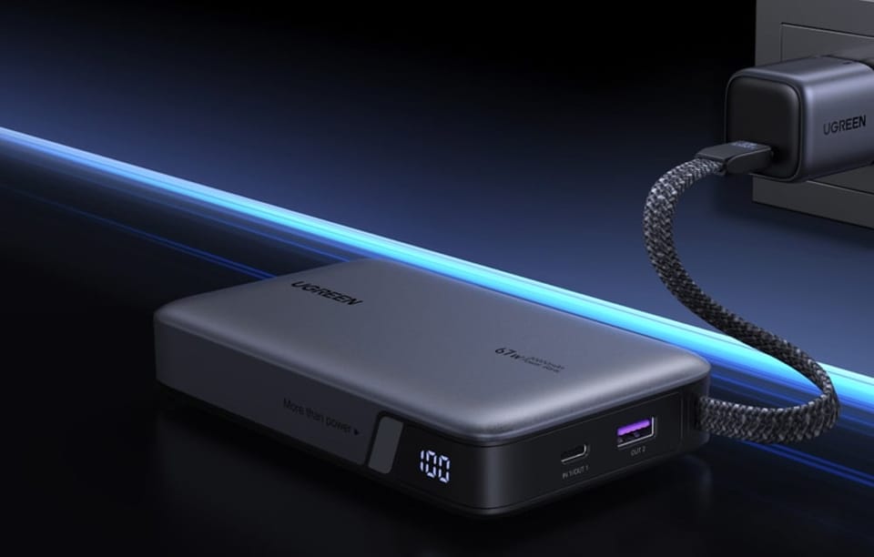Szary powerbank Ugreen podłączony do gniazda zasilania na ciemnym tle