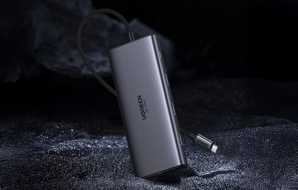 Hub UGREEN ustawiony pionowo na ciemnym tle z widocznym przewodem USB-C i bocznymi portami.