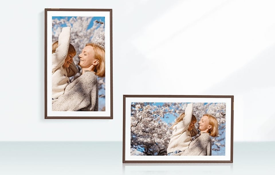 Pionowy i poziomy ekran cyfrowej ramki z tą samą fotografią kobiety trzymającej dziecko na tle kwitnących drzew