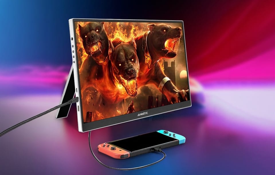Przenośny monitor z rozłożoną nóżką, podłączony kablem do leżącej przed nim konsoli do gier.