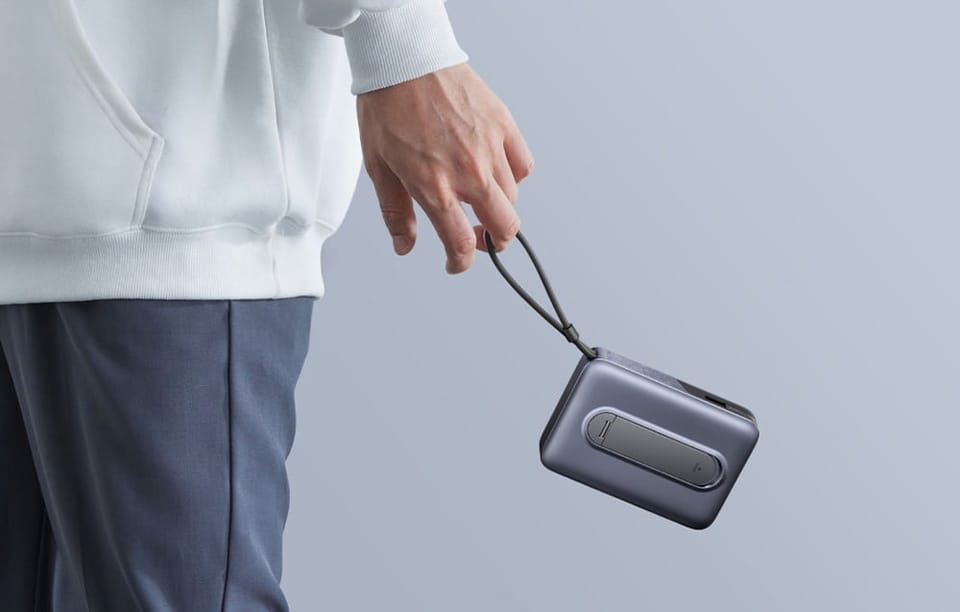 Osoba trzyma kompaktowy powerbank UGREEN za dołączoną pętlę do przenoszenia.