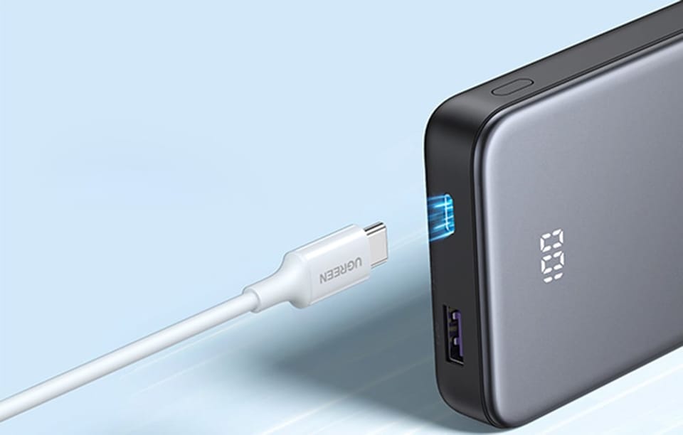 Kabel USB-C zbliżający się do podświetlonego portu wejściowego w powerbanku Ugreen.