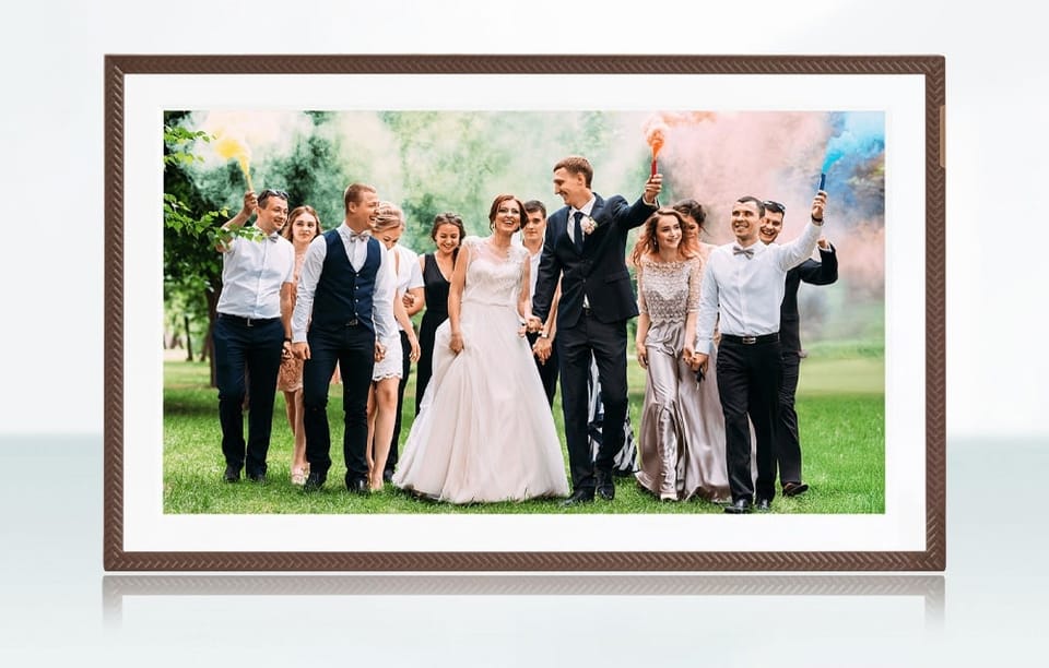 Cyfrowa ramka z fotografią pary młodej i gości weselnych trzymających kolorowe race na zielonej trawie