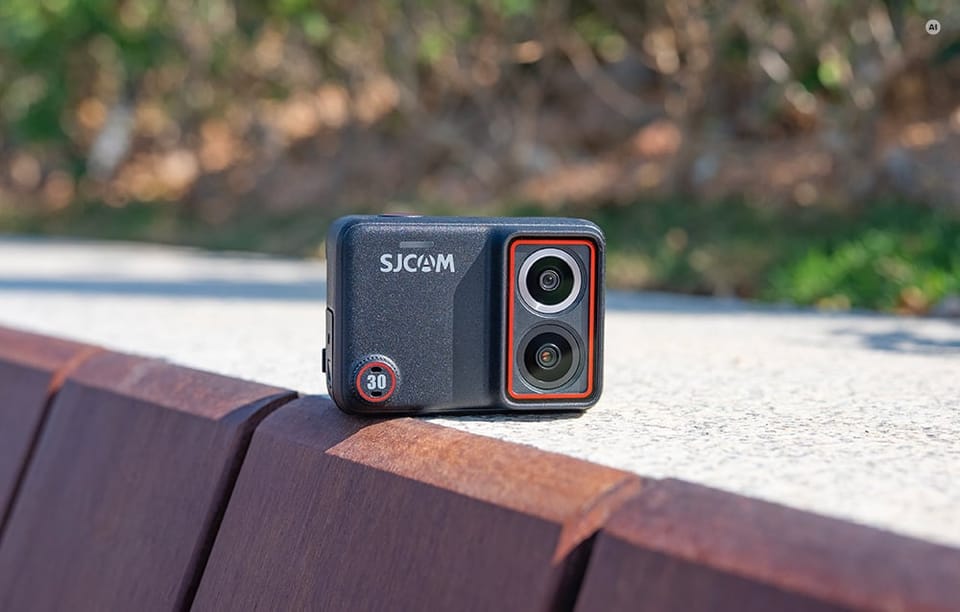 Kamera sportowa SJCAM postawiona w pozycji poziomej na ławce w parku.