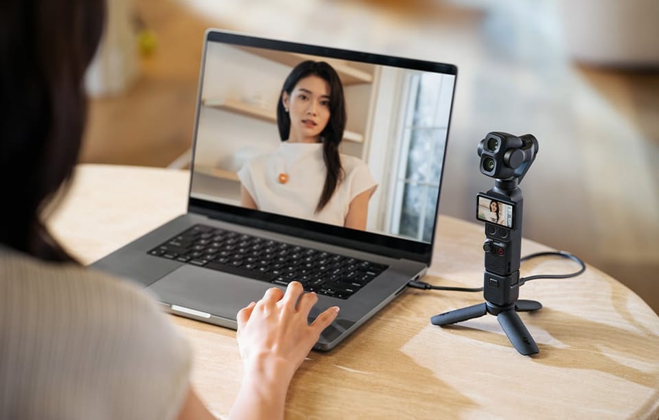 Kobieta przy laptopie używa małej kamery na statywie jako kamerki internetowej podczas wideorozmowy