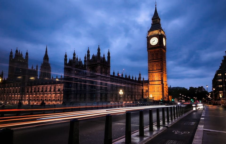 Oświetlona wieża Big Ben w Londynie o zmierzchu ze smugami świateł przejeżdżających aut.